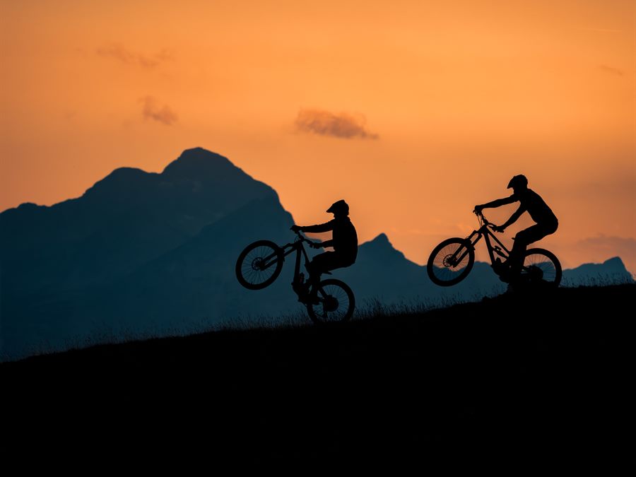 Two mountain bikers on a ridge against the light