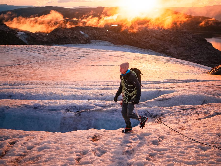 Roped hiker crossing a glacier at sunrise